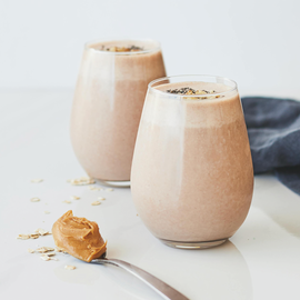  Two glasses of creamy smoothie made with peanut butter and oats.