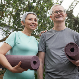 Senior man and woman with yoga mats, preparing for a workout session.